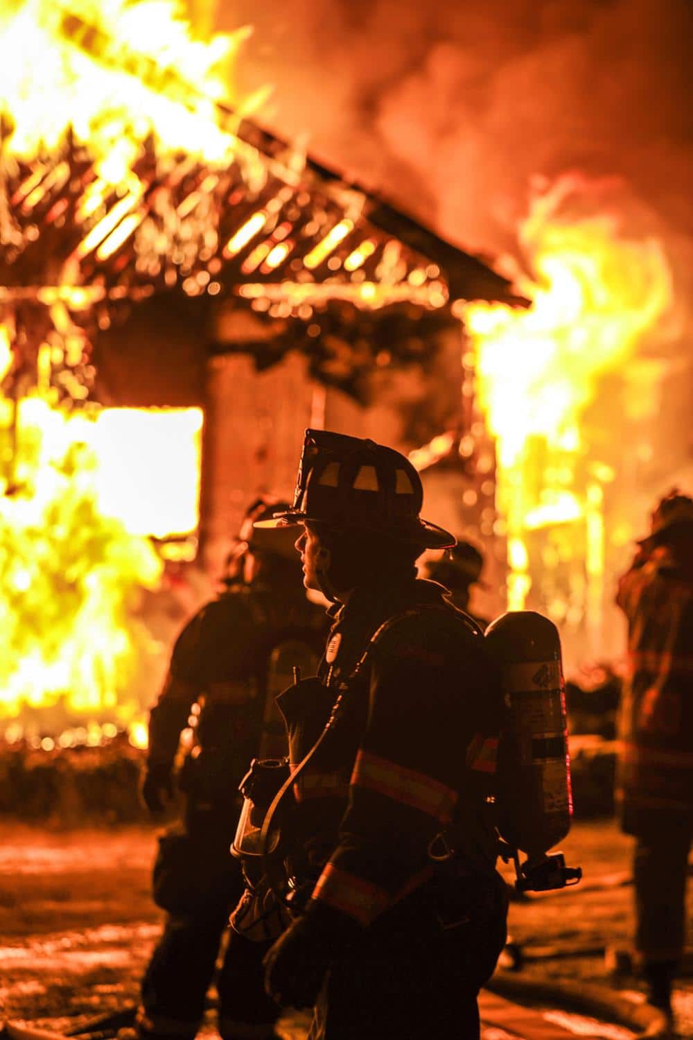 firefighters outside of a home that is burning